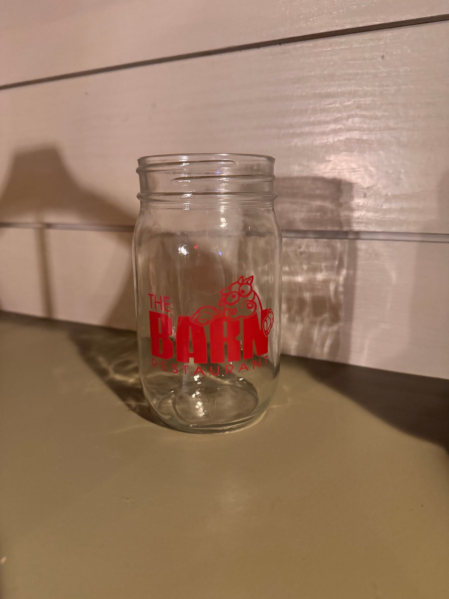 Clear glass mason jar with red Black River Barn restaurant logo